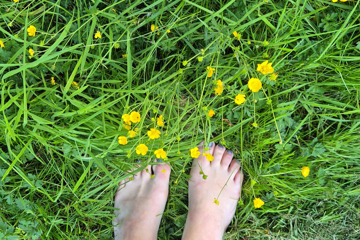 Feet standing on grass with yellow flowers